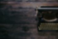 an image of an oldfashioned typewriter of a brown wooden desktop